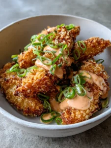 Nahaufnahme von goldbraun frittiertem Bang Bang Chicken mit Panko-Panade in einer Schale.