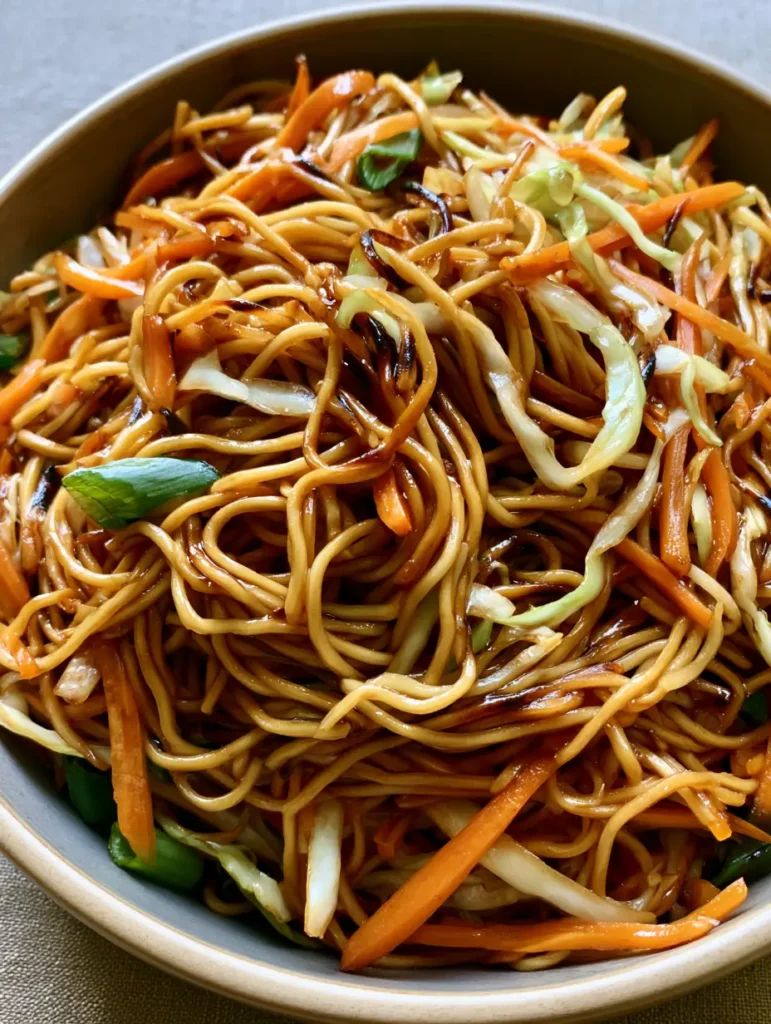 Nahaufnahme von gebratenen Eiernudeln mit Karotten und Kohl in einer Keramikschüssel. (Chow Mein Rezept)