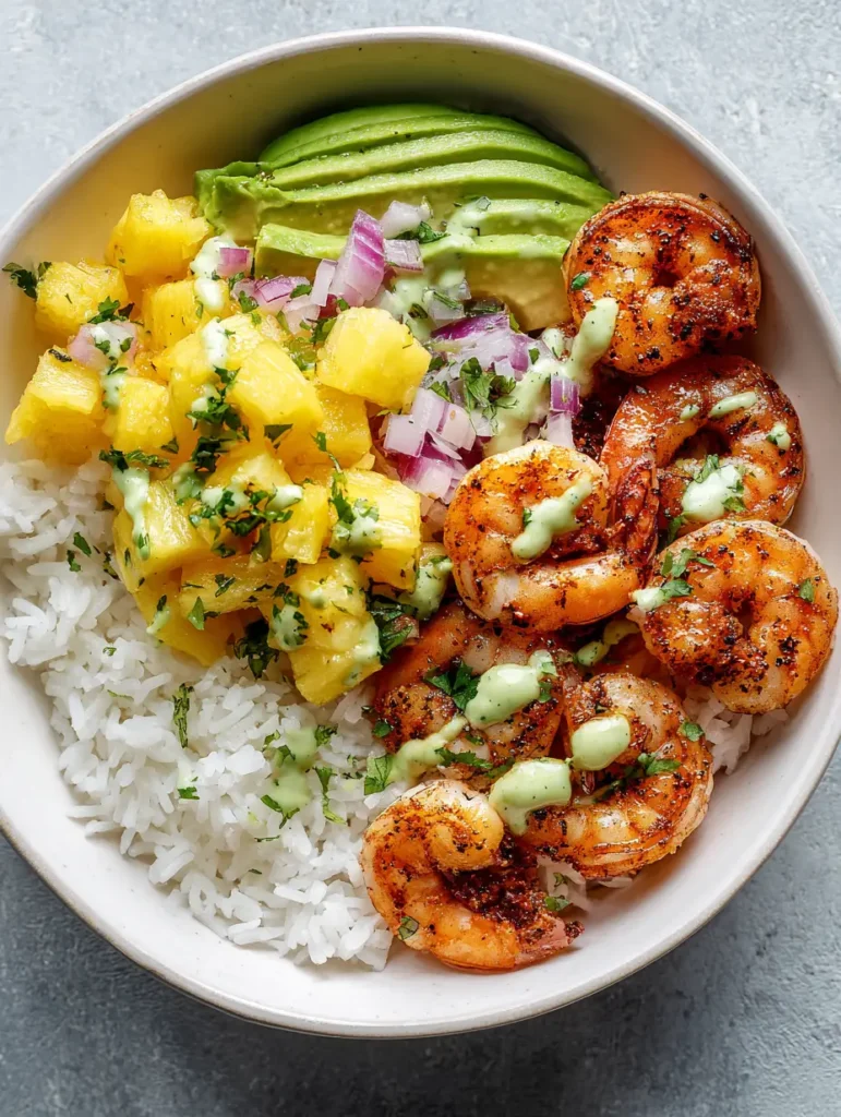 Garnelen-Reis-Bowl mit fruchtiger Ananas-Salsa & Avocado-Crema 1 Schüssel mit Jasminreis, Avocado-Spalten und Garnelen-Reis-Bowl Komponenten auf grauem Hintergrund.