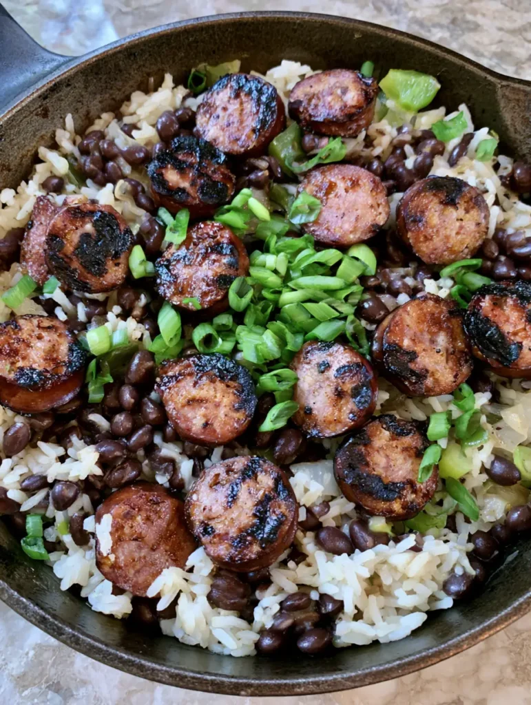 Nahaufnahme von One-Pot-Gericht mit Würstchen, deutlich sichtbare gebräunte Wurstscheiben und grüner Paprika.