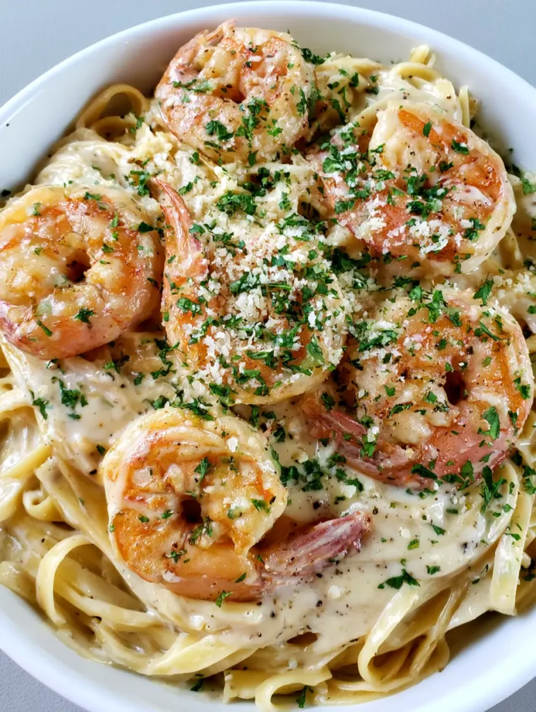 Garnelen Pasta Alfredo: Das ultimative Rezept für cremigen Genuss 1 Servierfertige Garnelen Pasta Alfredo mit viel Parmesan und frischem Pfeffer in einer weißen Schale.