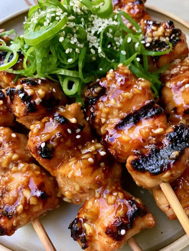 Honig-Knoblauch-Hähnchenspieße: Saftig, klebrig & unwiderstehlich 1 Gegrillte Hähnchenwürfel an Spießen mit reichlich Sesam und frischen grünen Zwiebelringen.