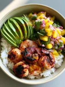 Nahaufnahme einer Garnelen-Bowl mit perfekt gebräunten Garnelen, reifer Avocado und leuchtend gelber Mango-Salsa.