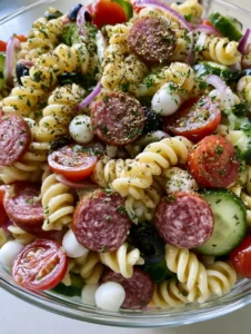 Nahaufnahme eines italienischen Protein-Nudelsalats mit Kirschtomaten, Mozzarella-Perlen und Salami.