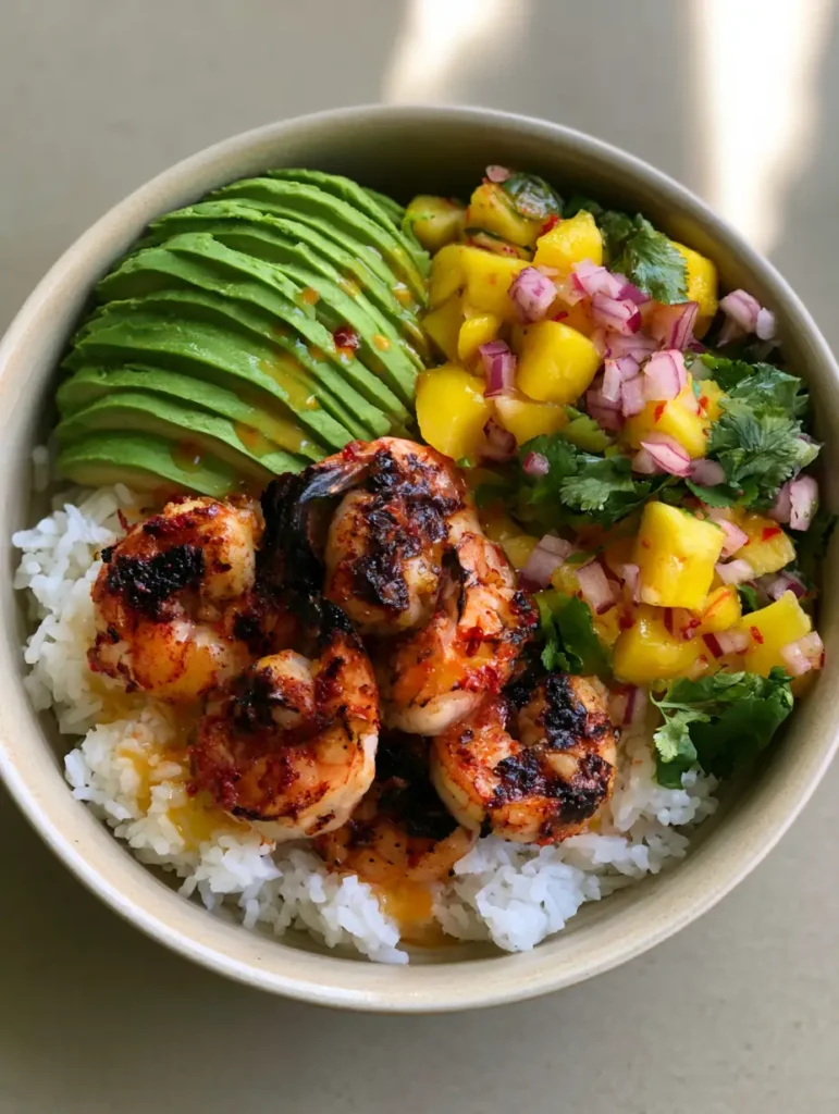 Angerichtete Garnelen-Bowl mit weißem Reis, Avocado und Chili-Limetten-Dressing in einer Keramikschale.