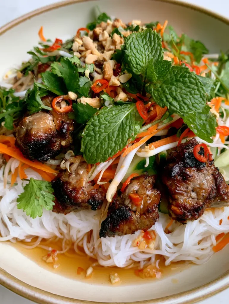 Nahaufnahme einer Schüssel Vietnamesischer Nudelsalat mit hellem Zitronengras-Schweinefleisch und Karotten.