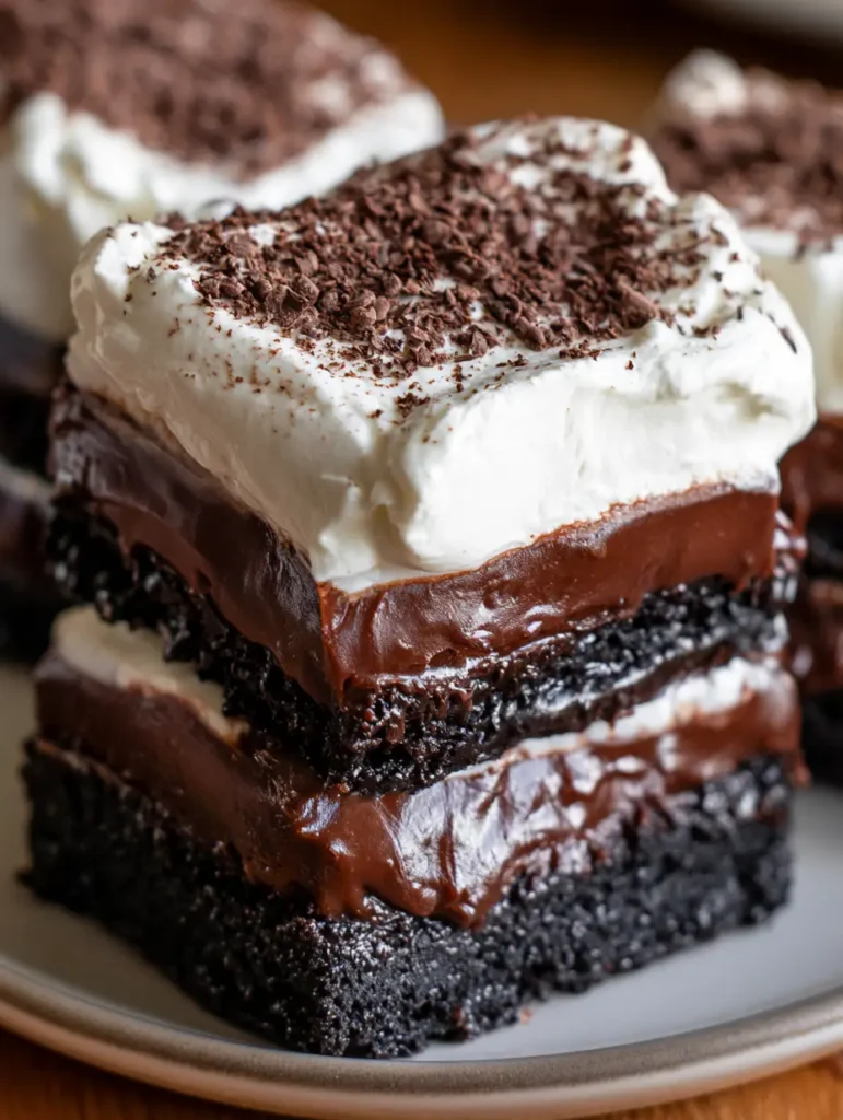 Schokoladen-Creme-Schnitten: Das ultimative Schicht-Dessert mit Oreo-Boden 1 Gestapelte Schokoladen-Creme-Schnitten auf einem hellen Teller mit Schokoladenraspeln obenauf.