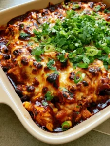 Nahaufnahme der goldbraunen Käsekruste auf einem Hähnchen-Enchilada-Auflauf mit schwarzen Bohnen und Mais.