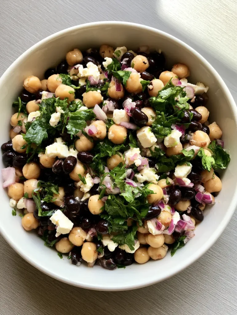 Kichererbsen-Schwarzbohnen-Salat: Das ultimative 10-Minuten-Rezept 2 Nahaufnahme von Kichererbsen, schwarzen Bohnen und Feta mit Limettendressing.