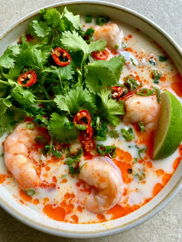 Thai Kokos Garnelensuppe serviert in einer Schale mit frischen Frühlingszwiebeln und Koriander.
